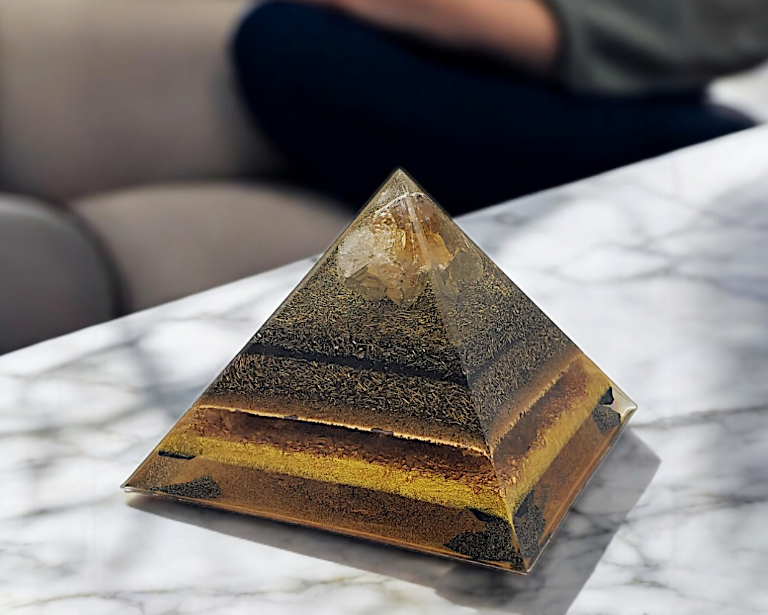 Pyramid-shaped object on a marble surface with a blurred person in the background